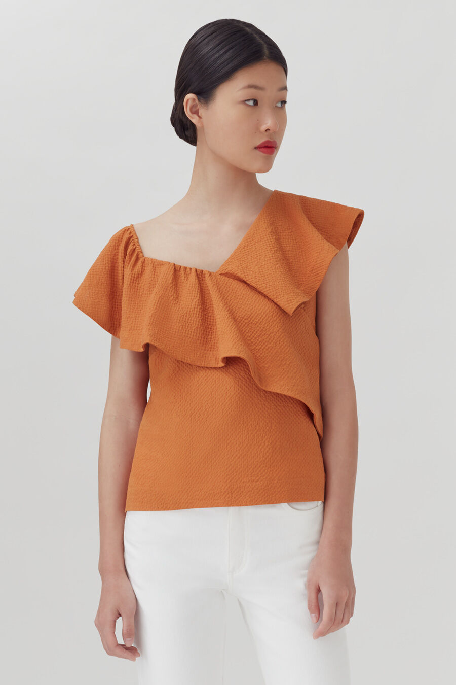 Woman in blouse with ruffled neckline, standing indoors