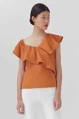 Woman in blouse with ruffled neckline, standing indoors