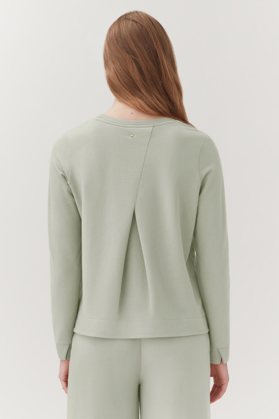 Woman seen from behind wearing a top with a back split design.