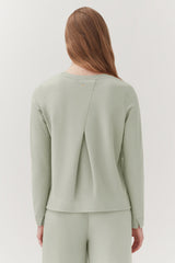 Woman seen from behind wearing a top with a back split design.