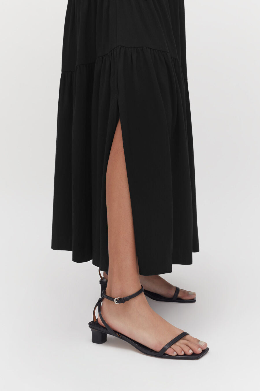 Person wearing a long skirt and heeled sandals showing one leg