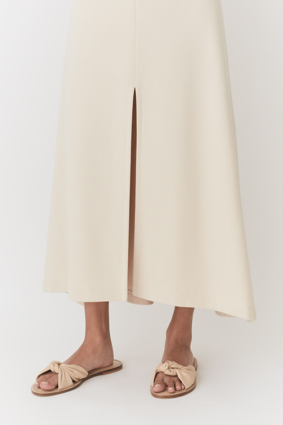 Woman standing in a split skirt and sandals.