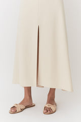 Woman standing in a split skirt and sandals.