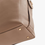 Close-up of a textured handbag with metallic studs and a strap attachment.