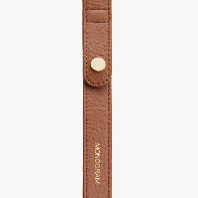 Strap with snap fastener and embossed text.