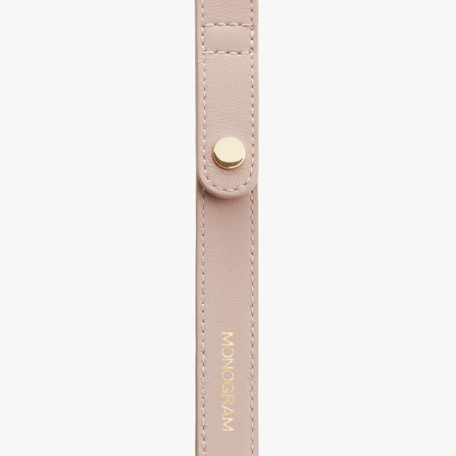 Close-up of a strap with stitched edges and a metal snap button.