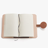 Open notebook with a strap closure on a plain surface.