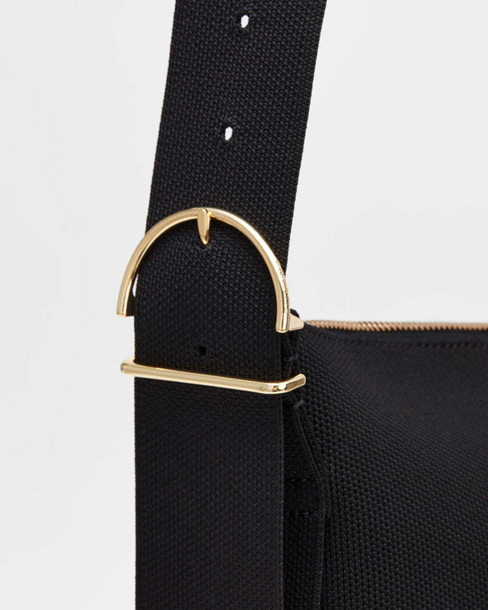 Close-up of a bag strap with metal buckle and adjustment holes.