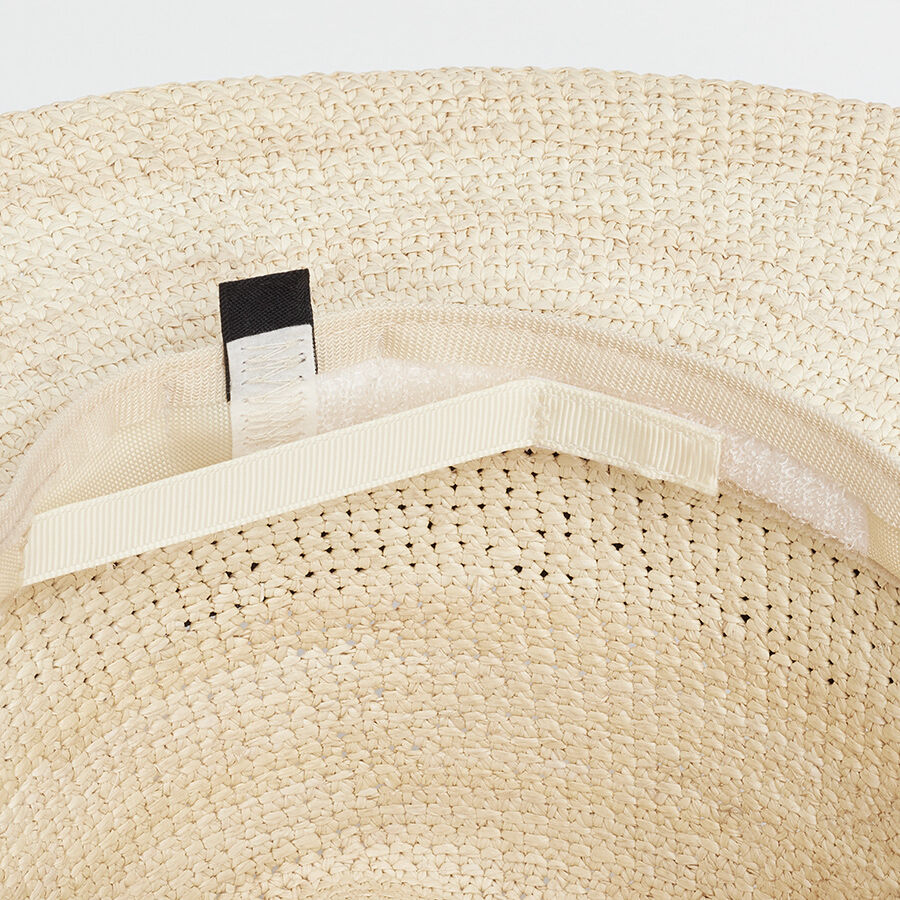 Close-up of a woven hat with a label and thin inner band.
