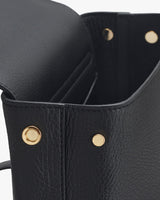 Close-up of a handbag showing the top edge and rivet details.