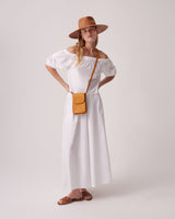 Woman in a dress, hat, and sandals with hands on hips