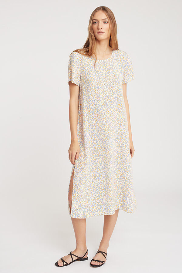 Woman in a patterned dress standing with one hand on her hip.