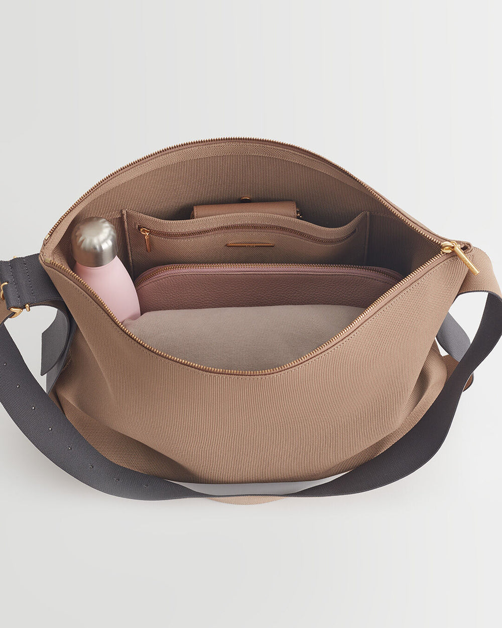 Open handbag showing internal compartments with a bottle inside.