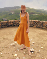 Woman in a dress and hat standing on a path with scattered petals.