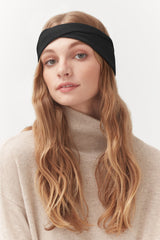 Woman with headband and turtleneck sweater, looking at the camera.