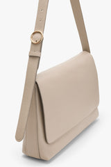 Shoulder bag with a textured strap and circular metal buckle.