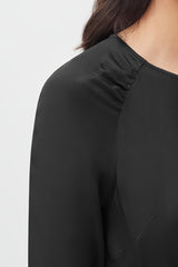 Close-up of a person wearing a top with a gathered shoulder detail.