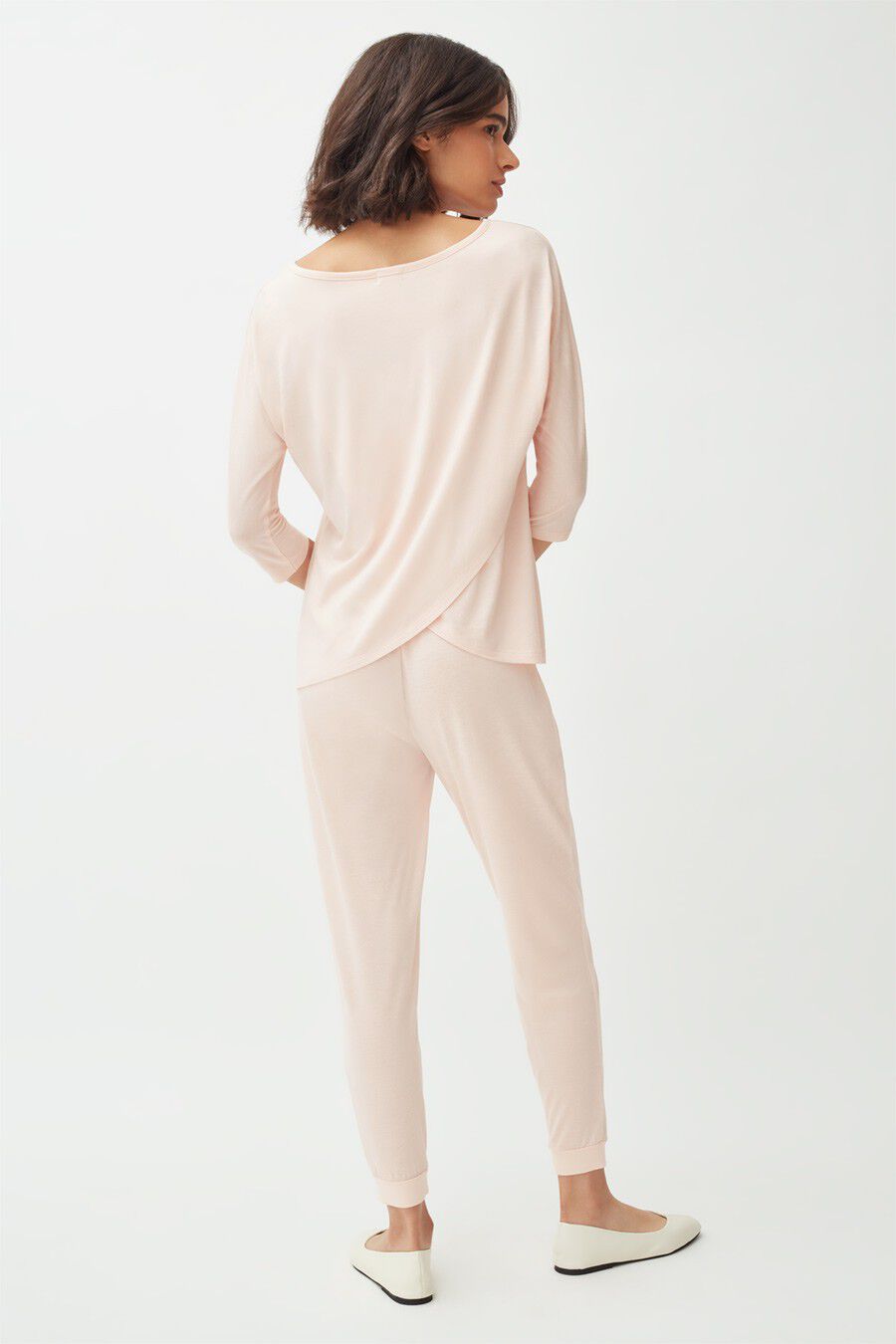 Woman standing, viewed from the back, wearing a casual outfit.