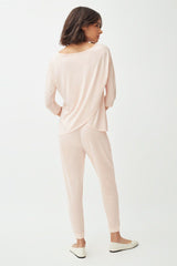 Woman standing, viewed from the back, wearing a casual outfit.