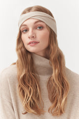 Woman with headband and turtleneck sweater looking at camera.