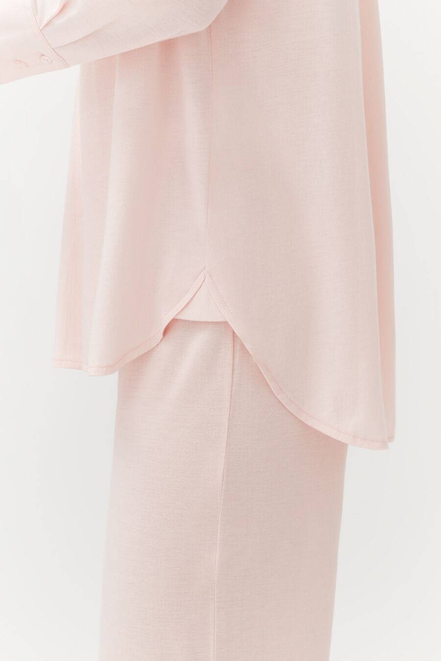 Close-up of a person wearing a layered top and fitted pants.