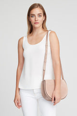 Woman standing with a shoulder bag.