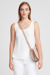 Woman wearing a sleeveless top and pants, carrying a shoulder bag across her chest.