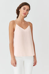 Woman in a sleeveless top and white pants standing