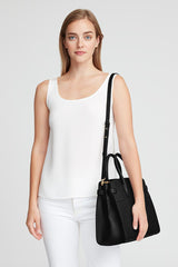 Woman standing with a handbag over her shoulder.