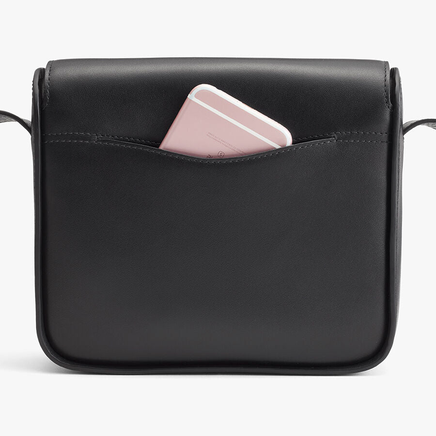 A handbag with a smartphone peeking out from the top.