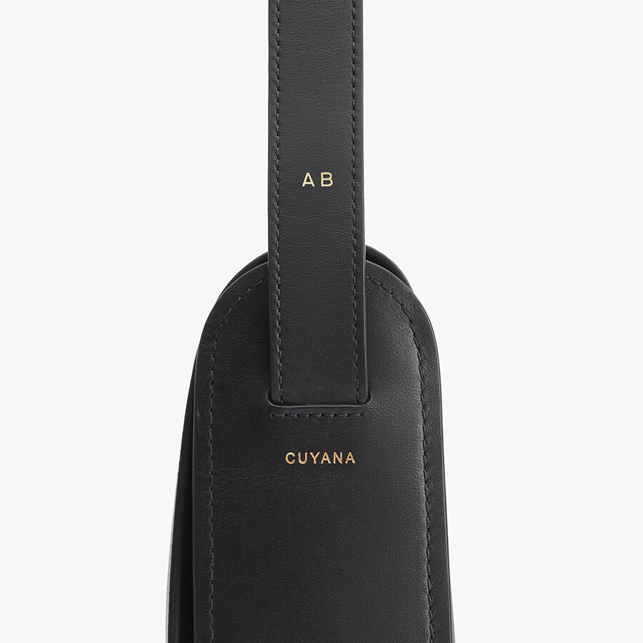 Close-up of a personalized strap on a bag with stitched details and brand name.
