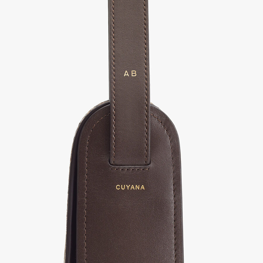 Close-up of a luggage tag with initials and a brand name.