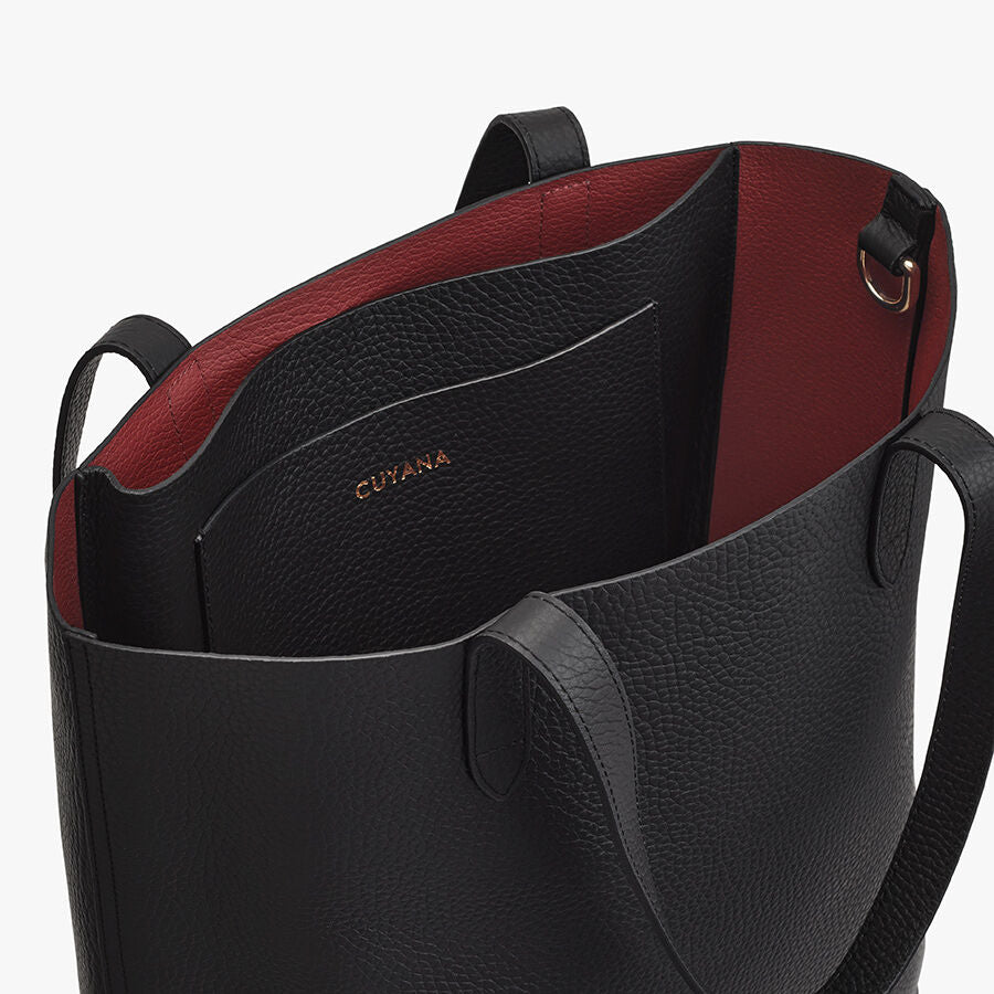 Close-up of an open leather tote bag with a visible brand logo inside.
