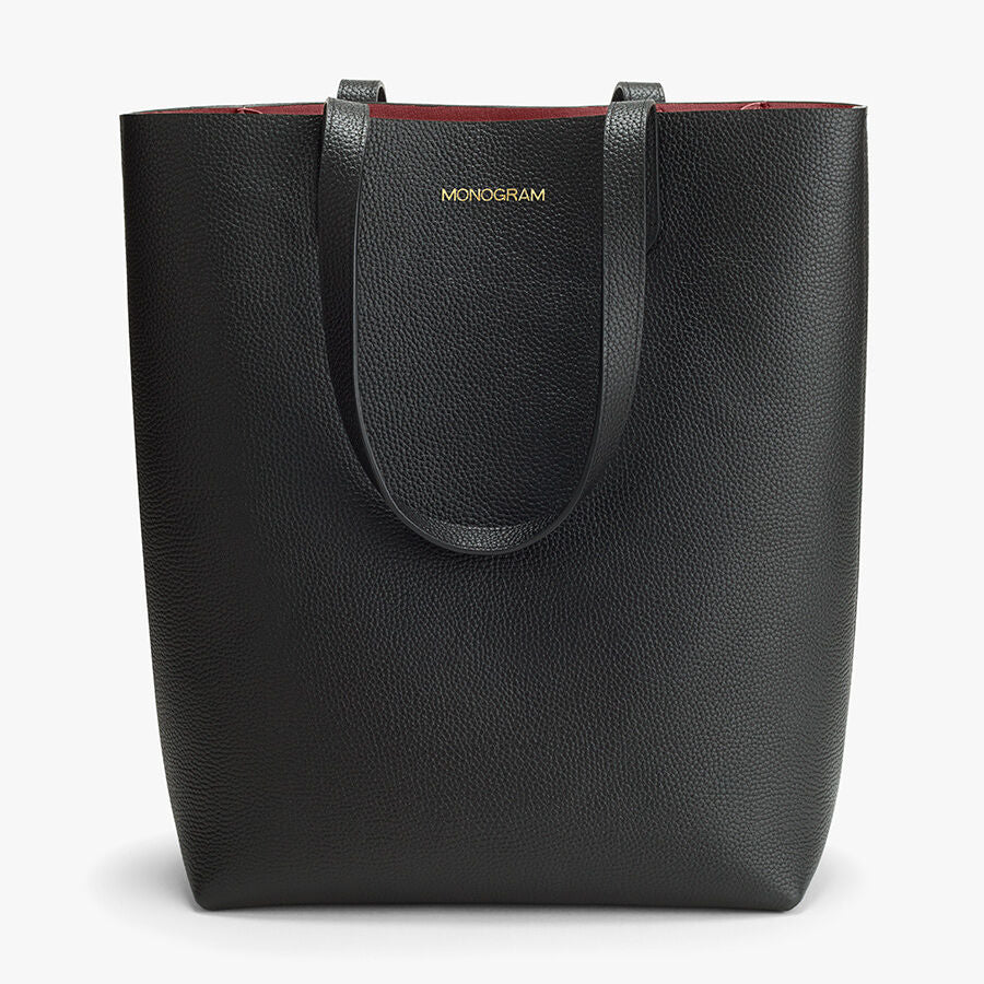 Textured tote bag with brand label and handles on top.