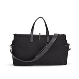 Handbag with top handles and a shoulder strap standing upright