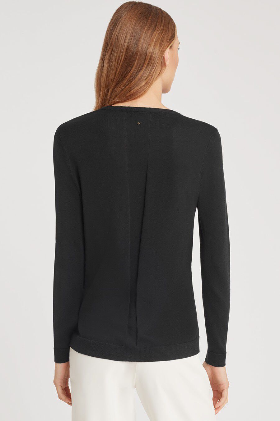 Woman wearing a long-sleeve top, viewed from the back.