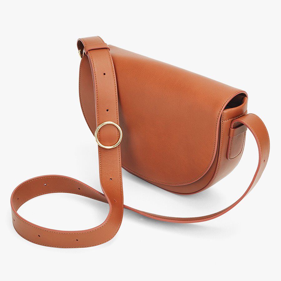 Leather shoulder bag with a circular metal clasp and adjustable strap.