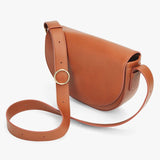 Leather shoulder bag with a circular metal clasp and adjustable strap.